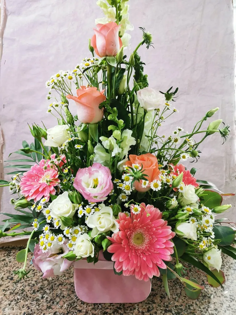 Arranjo em tons pastel com gérberas cor-de-rosa, lisianthus e rosas pêssego