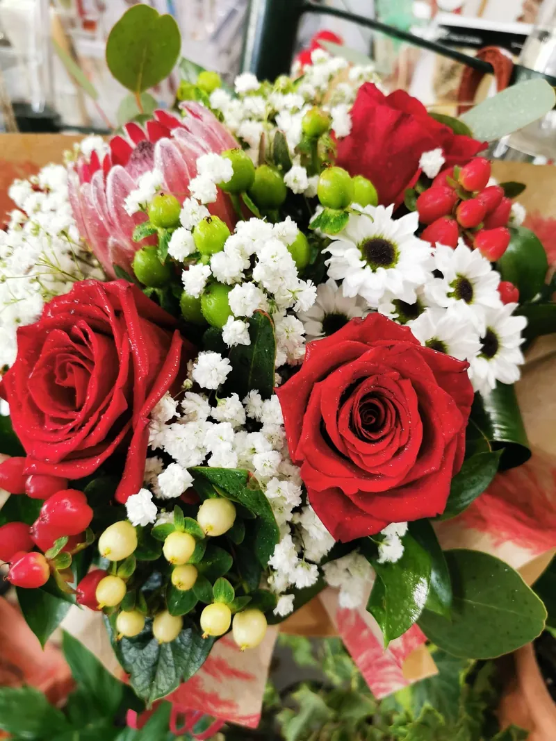 Arranjo de rosas vermelhas com margaridas brancas, hypericum e protea